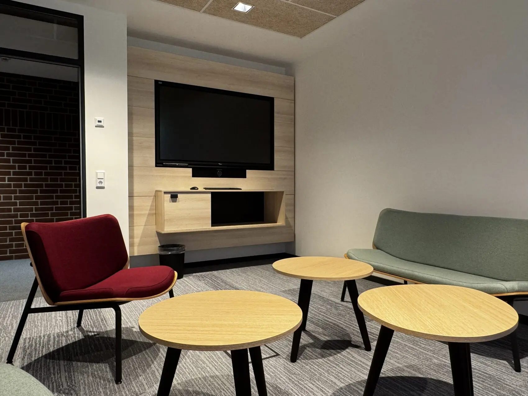 Lounge mit Medienwand, Loungesessel und Beistelltischen